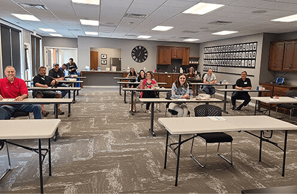 People sitting at desks in a classroom or training room setting.