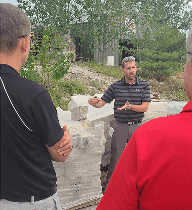 Man explaining stone construction to two people outdoors in Lincoln, Nebraska.