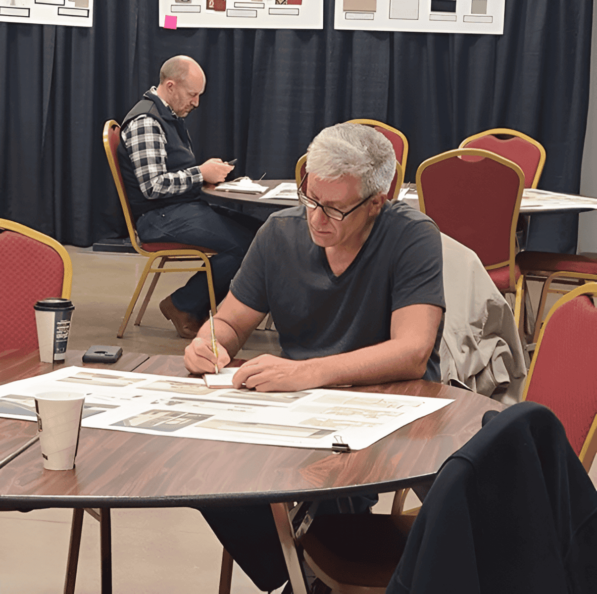 2022 Interior and Residential Design Two men working at tables, one writing, one on phone.