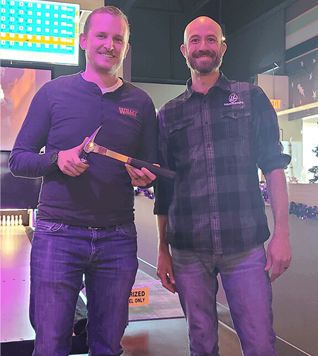 Two men at the 2023 Remodelers Holiday Party, one holding a trophy.