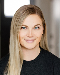 Smiling young woman with blonde hair and blue eyes in a professional setting.