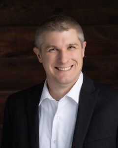 Professional man in suit smiling against wooden background.